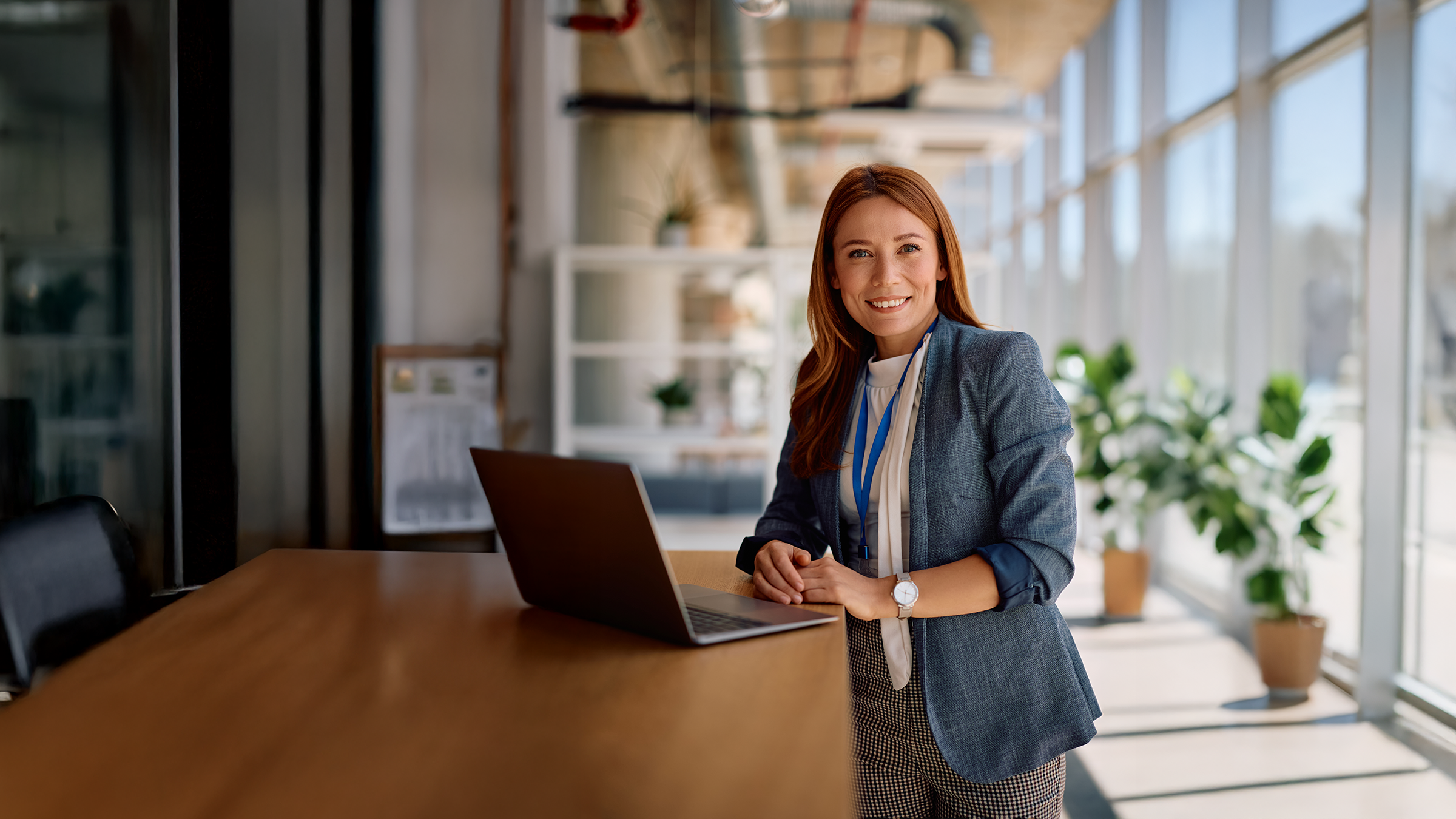 Medewerker Verzuimadministratie achter bureau met laptop in kantooromgeving.